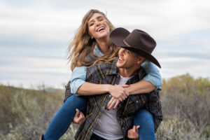 western wear young couple giving piggy back ride and laughing